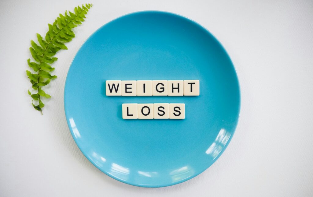 A blue plate with 'weight loss' tiles and a fern leaf on white background.