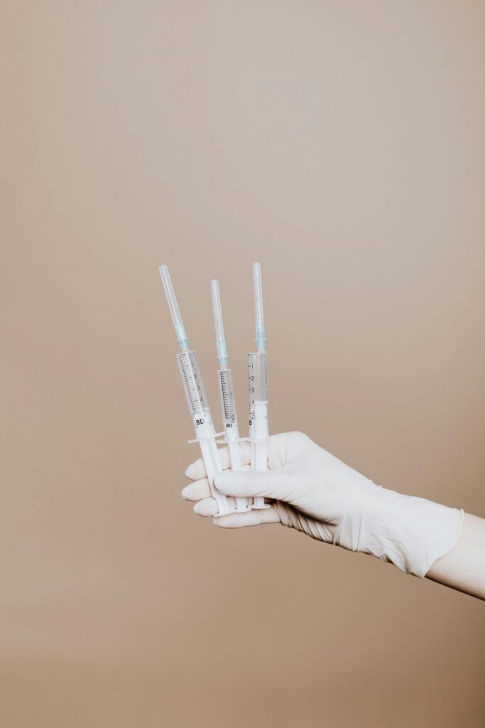 Close-up of gloved hand holding sterile syringes, symbolizing healthcare and vaccination.